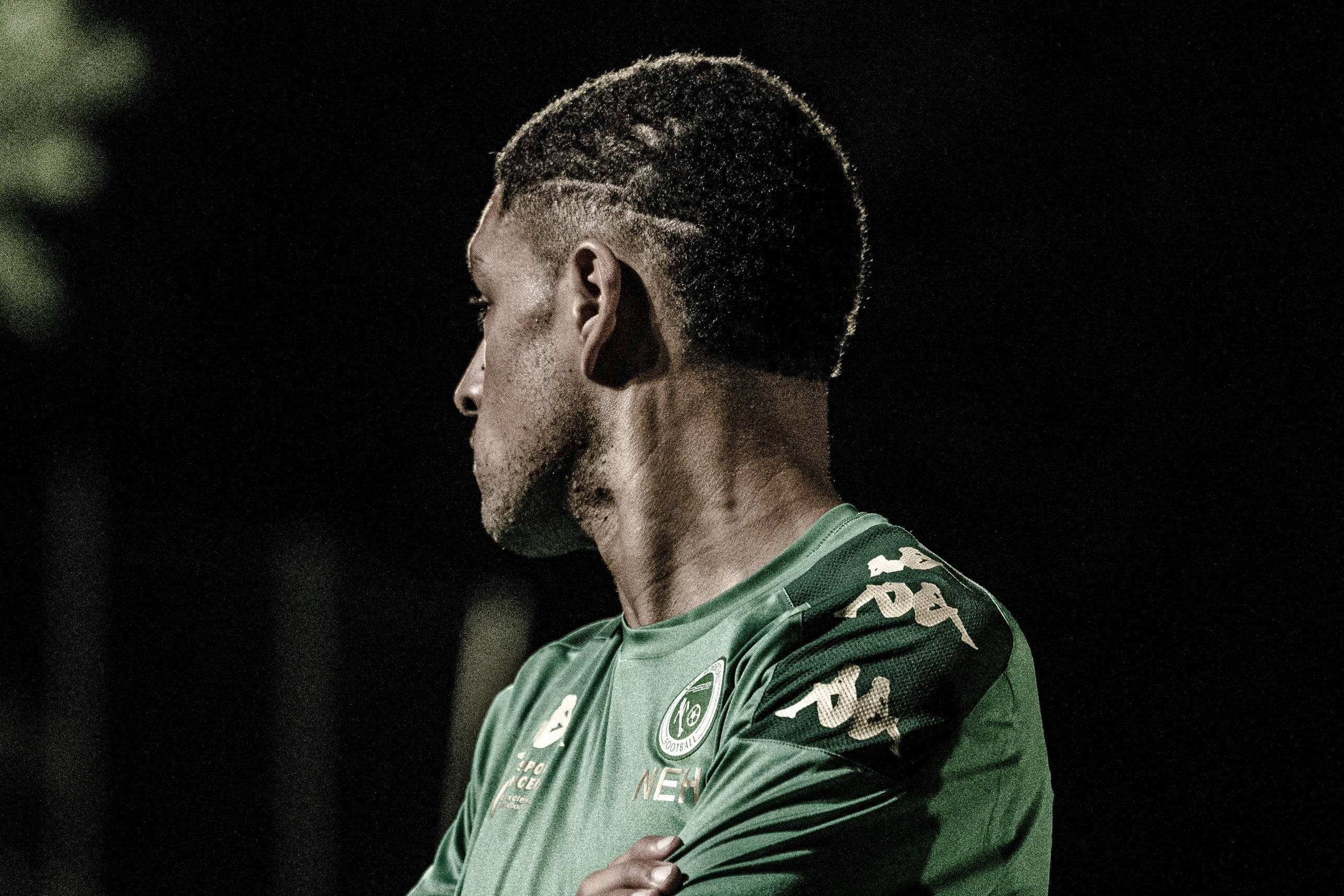 Footballeur de profil dans la pénombre, maillot vert