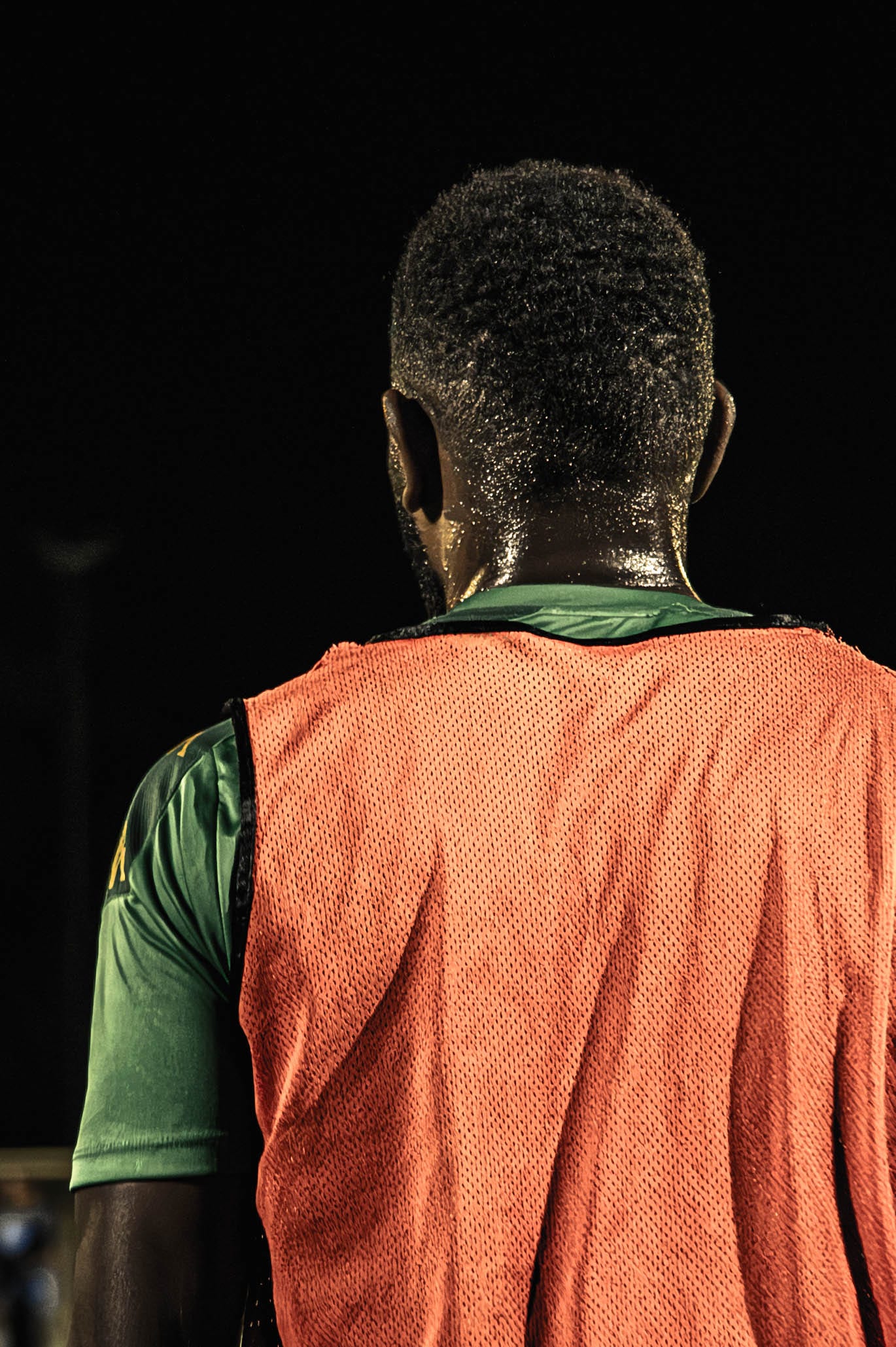 Footballeur de dos, chasuble orange sur maillot vert