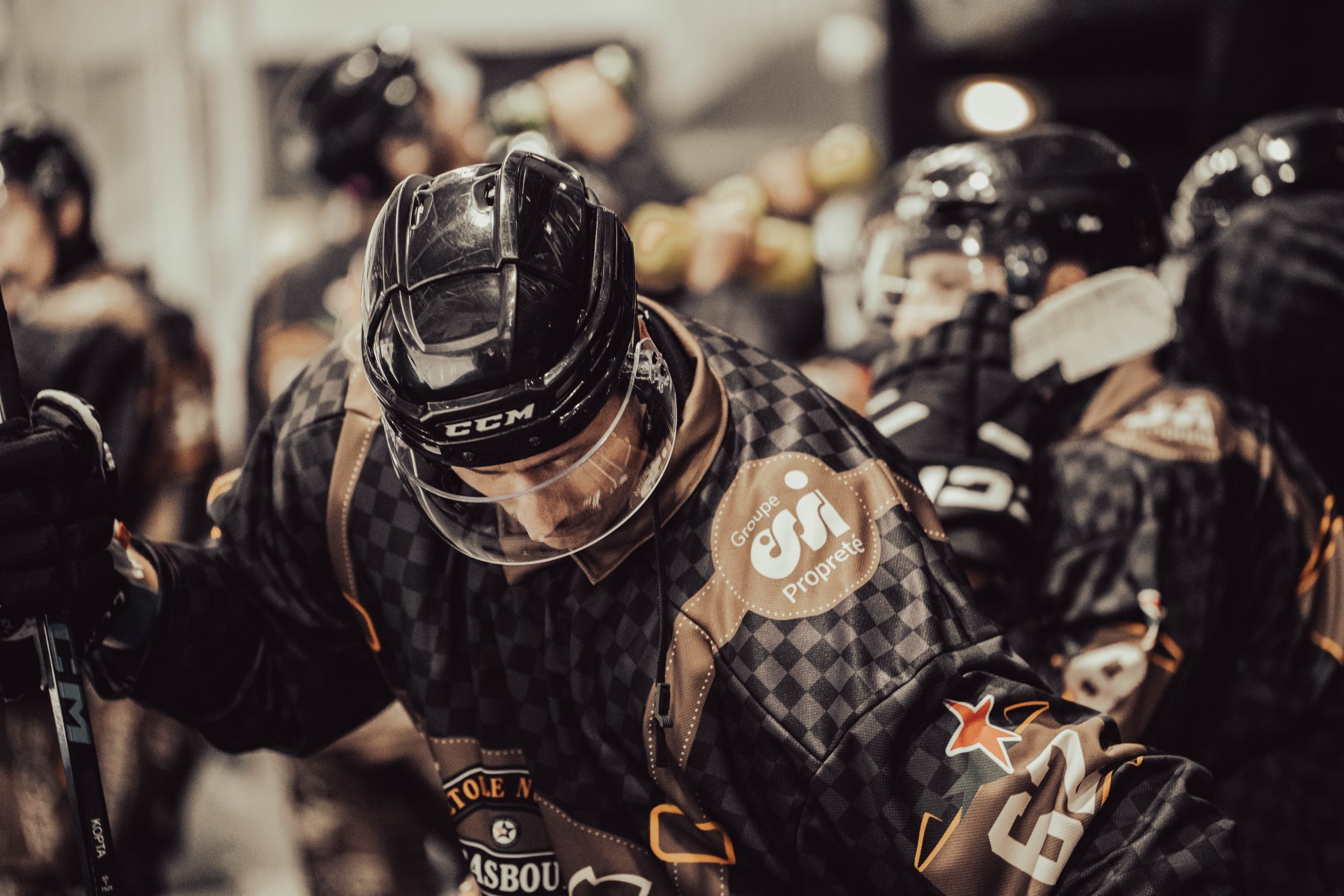 Joueur de hockey sur glace, casque baissé, au bord de la glace