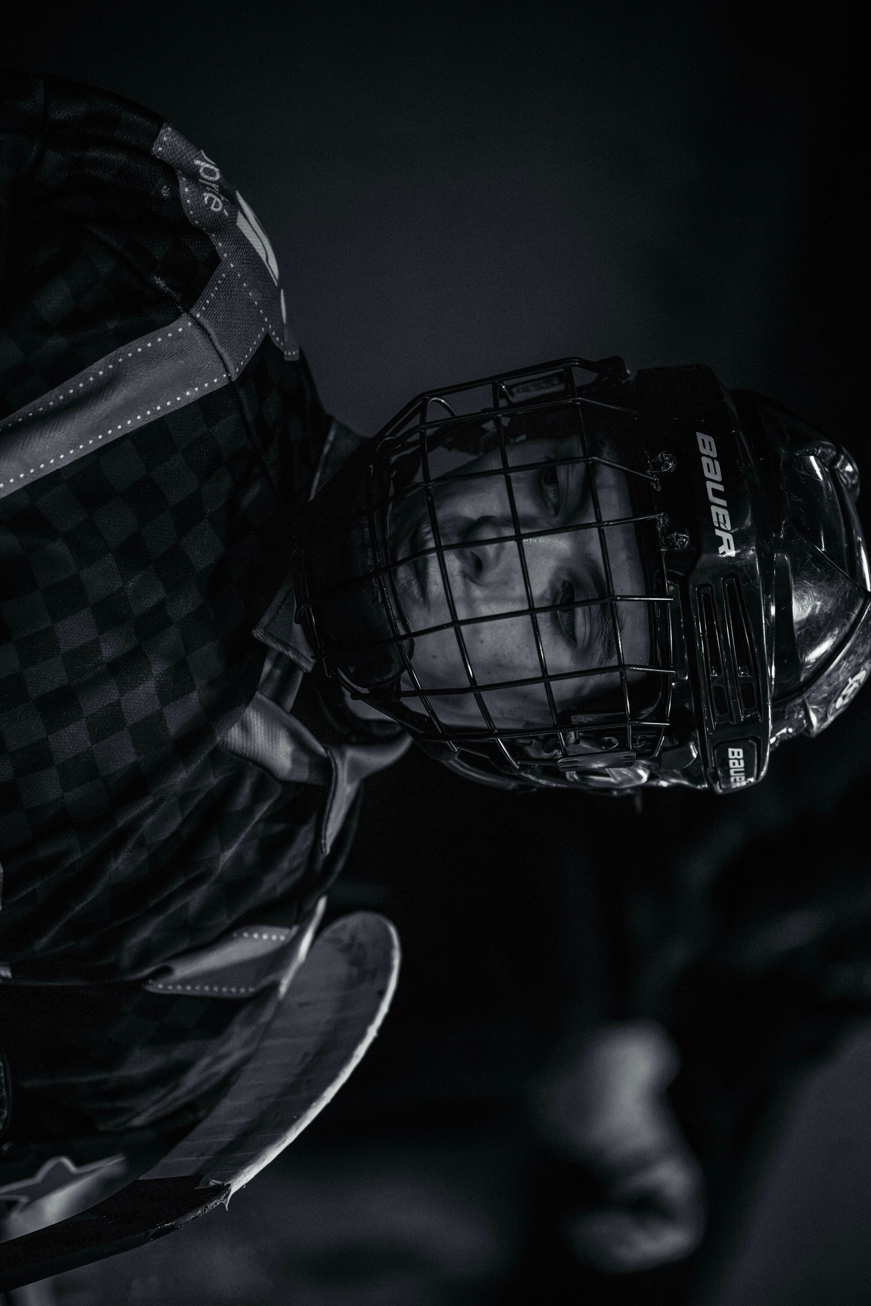 Portrait en noir et blanc d’un joueur de hockey derrière la grille de son casque